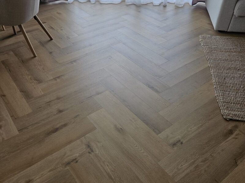 Salon z drewnianą podłogą jodełkową — realizacja Varia